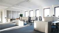 Luftigt kontorslandskap med ljusa möbler och dagsljus.