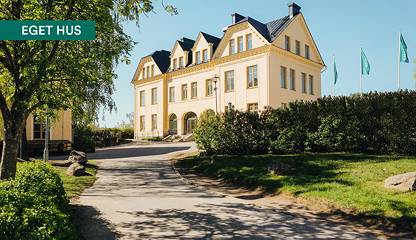 Fastigheten sedd från entrésidan med gångväg och grönska. Åldermansvägen 10